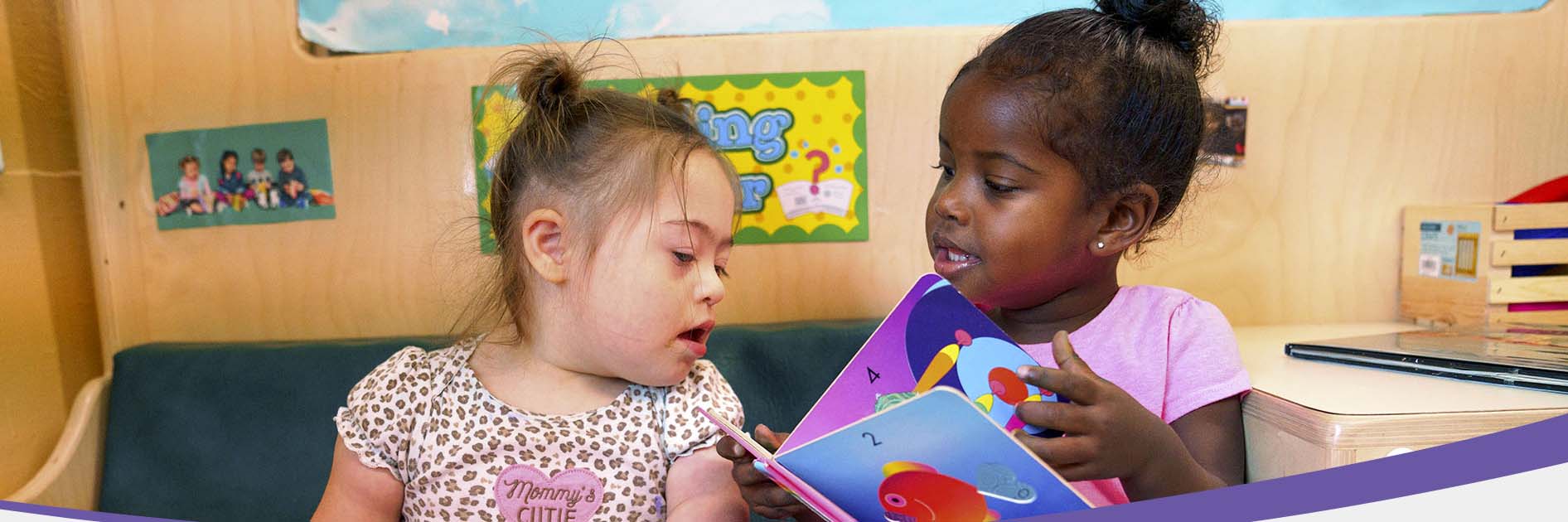 Two preschool students sharing a book